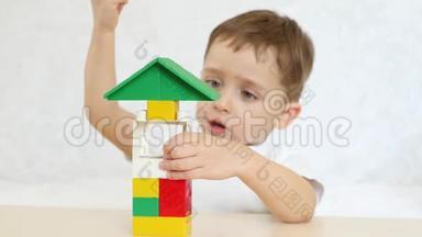 一个孩子正坐在一张白色背景的桌子上，用彩色<strong>积木</strong>玩耍。 孩子和<strong>玩具</strong>。 重点是<strong>玩具</strong>。